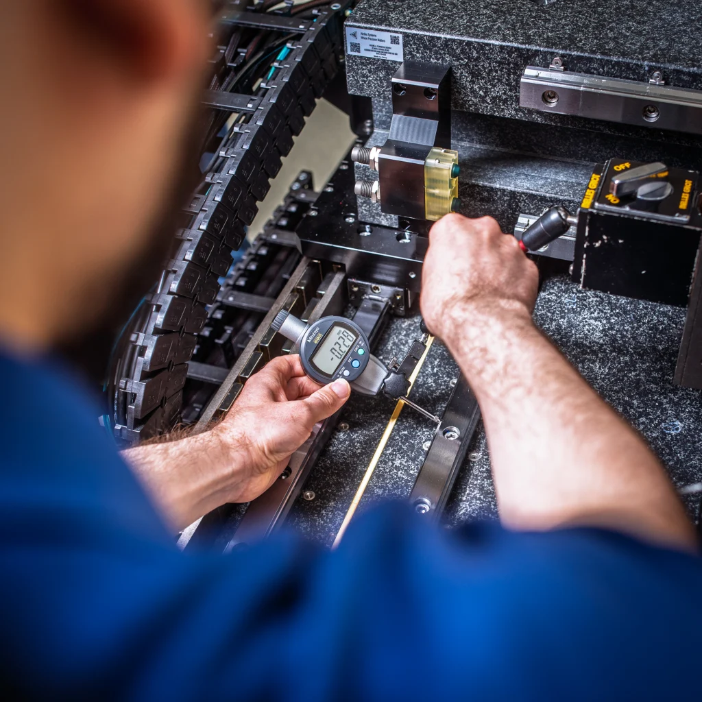 An engineer measuring alignment on a granite stage with a dial indicator